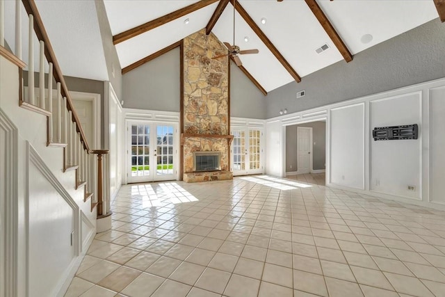 unfurnished living room featuring ceiling fan, light tile patterned floors, high vaulted ceiling, beamed ceiling, and a stone fireplace