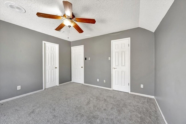 unfurnished bedroom featuring carpet flooring, a textured ceiling, vaulted ceiling, and ceiling fan