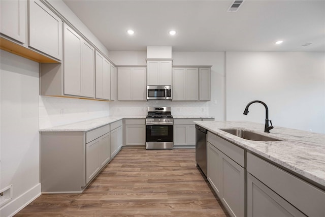 kitchen featuring gray cabinets, sink, appliances with stainless steel finishes, and light hardwood / wood-style flooring