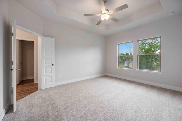 carpeted spare room featuring ceiling fan and a tray ceiling