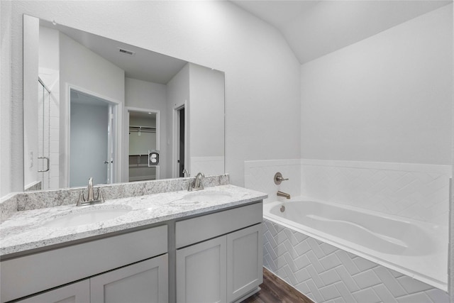 bathroom with plus walk in shower, vanity, lofted ceiling, and hardwood / wood-style flooring