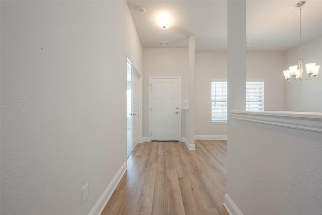 hallway featuring light hardwood / wood-style flooring and an inviting chandelier