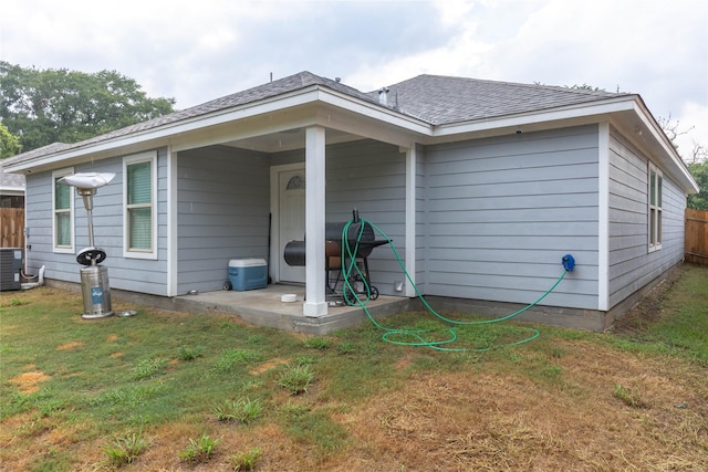 rear view of property with a patio area, a yard, and cooling unit