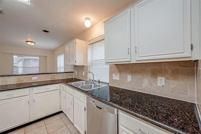 kitchen with dark stone counters, sink, light tile patterned floors, dishwasher, and white cabinetry