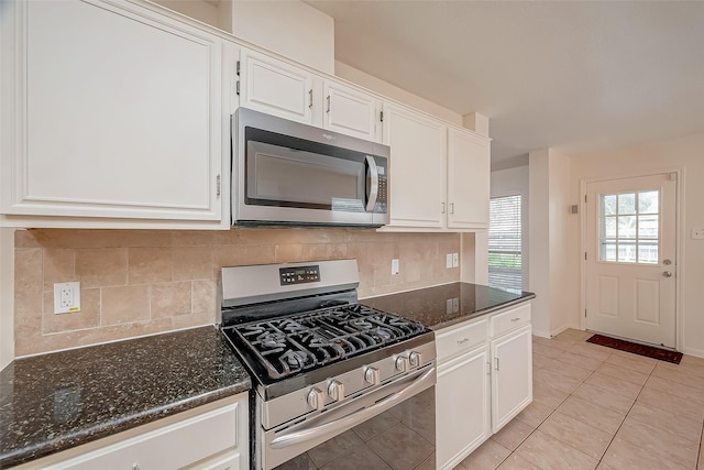 kitchen featuring white cabinets, light tile patterned floors, stainless steel appliances, and dark stone countertops