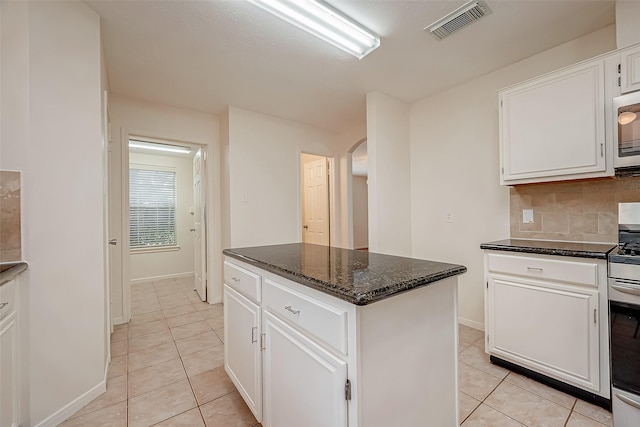 kitchen featuring electric range, white cabinets, light tile patterned floors, and a kitchen island