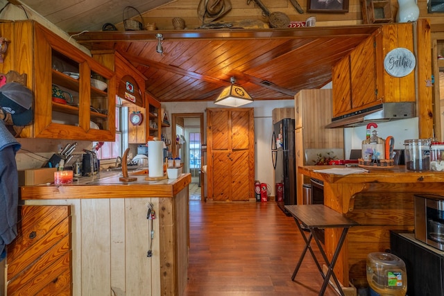 kitchen featuring black fridge, hardwood / wood-style floors, wood ceiling, and lofted ceiling