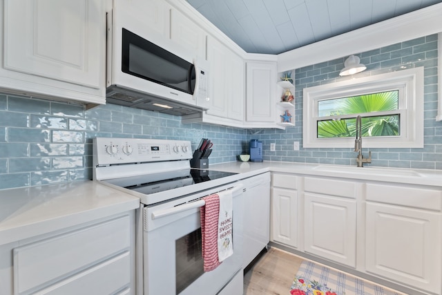 kitchen with sink, light hardwood / wood-style flooring, backsplash, white appliances, and white cabinets