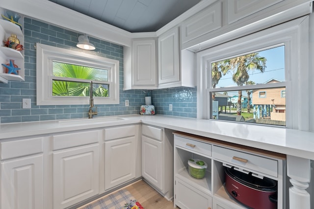 kitchen with white cabinets, tasteful backsplash, a wealth of natural light, and sink