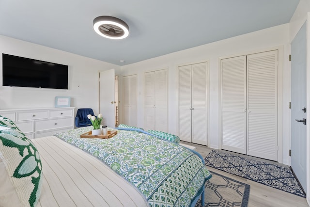 bedroom with light hardwood / wood-style flooring and multiple closets