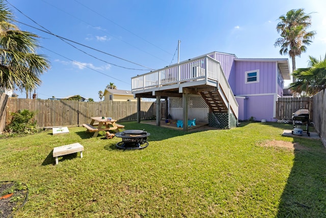 rear view of property featuring a deck, a lawn, and a fire pit