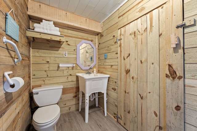 bathroom with hardwood / wood-style flooring, toilet, and wooden walls