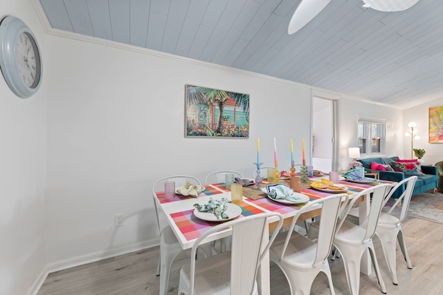 dining area with light wood-type flooring, ornamental molding, and wood ceiling