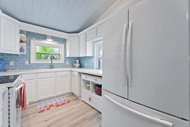 kitchen featuring sink, white refrigerator, white cabinets, range, and lofted ceiling