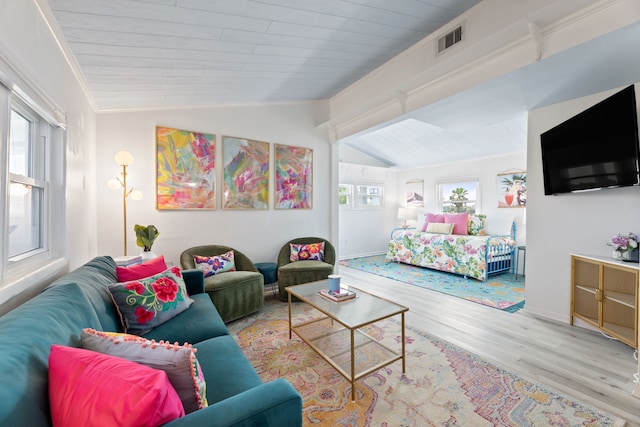 living room featuring ornamental molding, light hardwood / wood-style flooring, a wealth of natural light, and vaulted ceiling