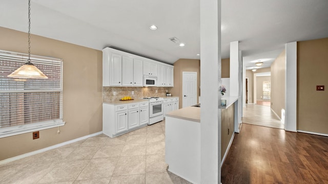 kitchen with light tile patterned floors, white appliances, white cabinetry, hanging light fixtures, and tasteful backsplash