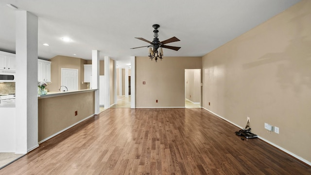 unfurnished living room with ceiling fan, sink, and light wood-type flooring