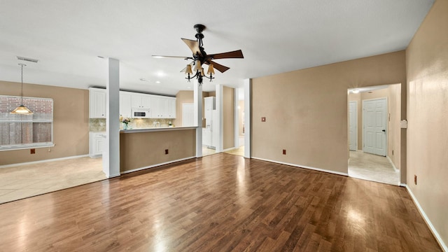 unfurnished living room with ceiling fan and hardwood / wood-style floors