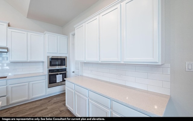 kitchen featuring white cabinets, decorative backsplash, oven, and built in microwave