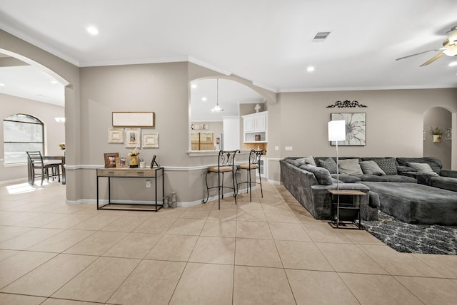 tiled living room with crown molding and ceiling fan