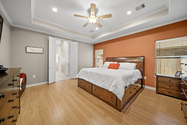 bedroom featuring a tray ceiling, light hardwood / wood-style flooring, ceiling fan, and crown molding