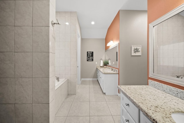 bathroom with tile patterned flooring, vanity, and a relaxing tiled tub