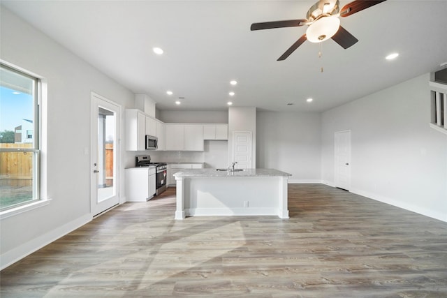 kitchen with a wealth of natural light, white cabinetry, an island with sink, and stainless steel appliances