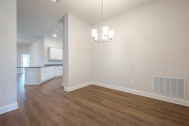 unfurnished dining area featuring dark wood-type flooring and an inviting chandelier