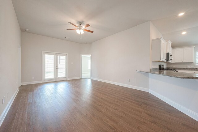 unfurnished living room featuring french doors, ceiling fan, and dark wood-type flooring