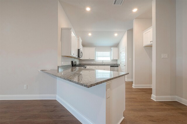 kitchen featuring kitchen peninsula, appliances with stainless steel finishes, dark wood-type flooring, dark stone countertops, and white cabinets