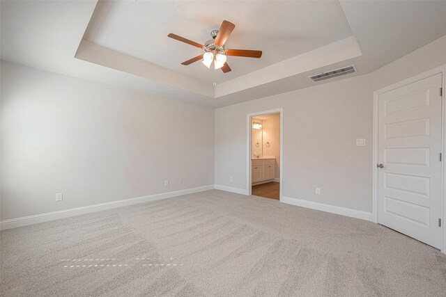 carpeted spare room featuring a tray ceiling and ceiling fan