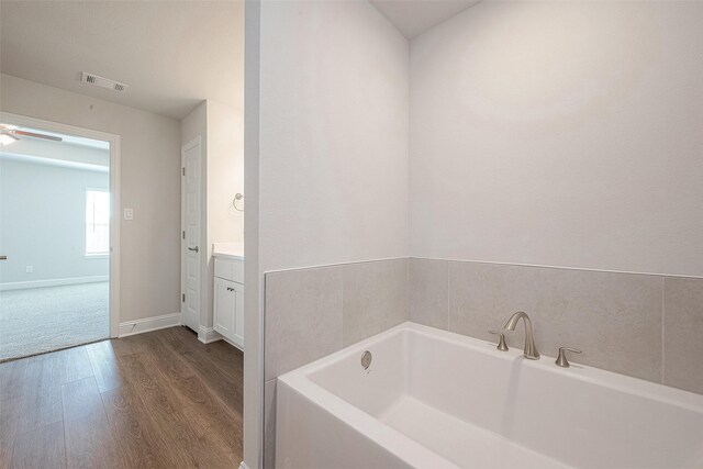 bathroom featuring vanity, hardwood / wood-style flooring, ceiling fan, and a bathing tub