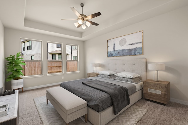 carpeted bedroom with ceiling fan, a raised ceiling, and multiple windows