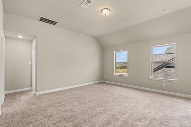 carpeted empty room featuring vaulted ceiling