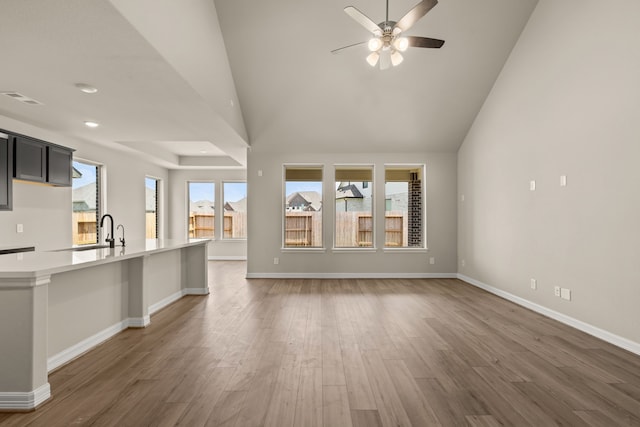 unfurnished living room with ceiling fan, dark wood-type flooring, and sink