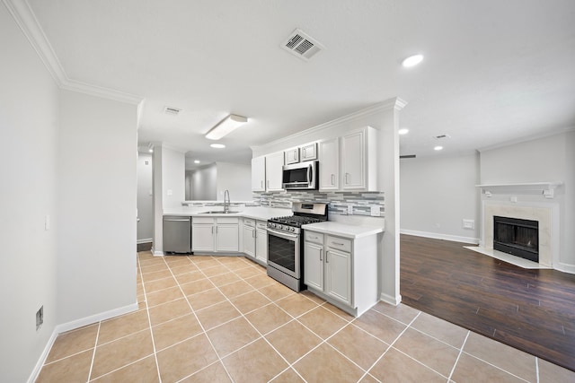 kitchen featuring backsplash, sink, light tile patterned floors, white cabinetry, and stainless steel appliances