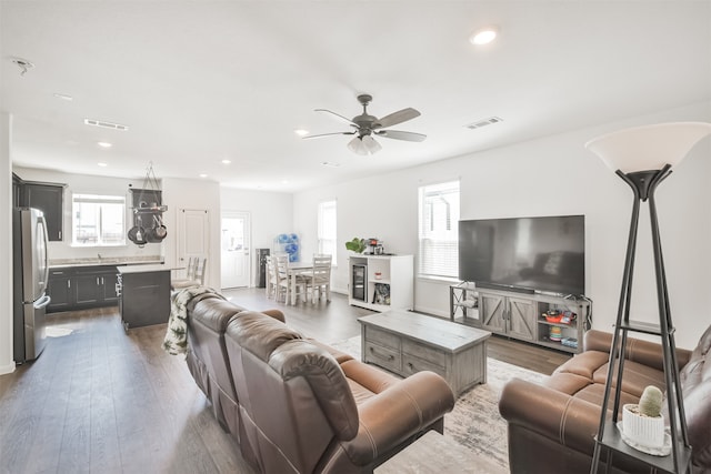 living room featuring wood-type flooring, ceiling fan, and sink