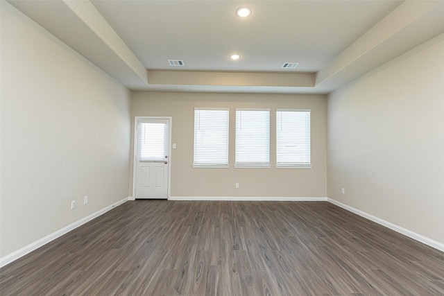 empty room featuring dark hardwood / wood-style floors and a raised ceiling