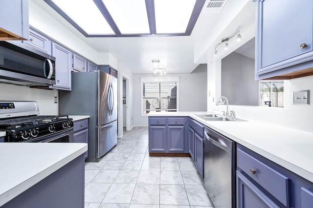 kitchen featuring kitchen peninsula, stainless steel appliances, sink, blue cabinetry, and light tile patterned floors