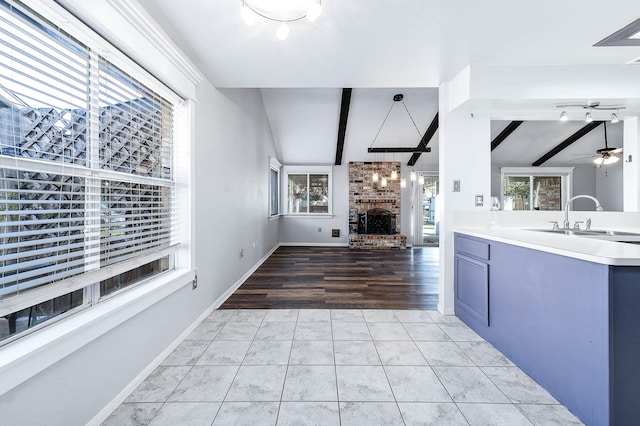 kitchen featuring sink, ceiling fan, a fireplace, plenty of natural light, and light tile patterned flooring