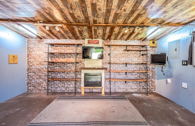 unfurnished living room with electric panel, track lighting, wooden ceiling, and brick wall