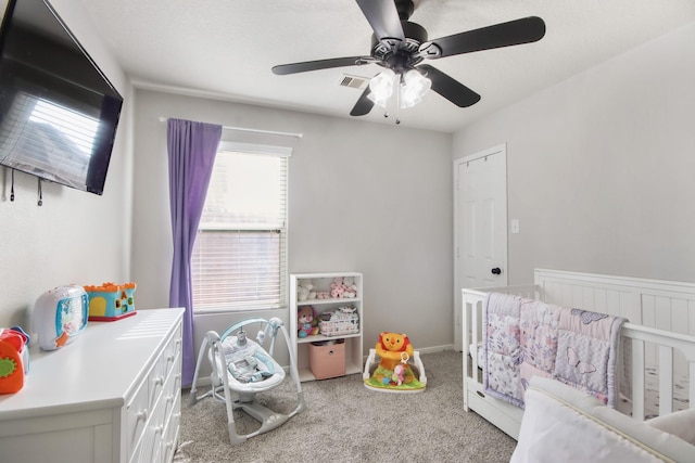 bedroom with ceiling fan, light carpet, and a nursery area