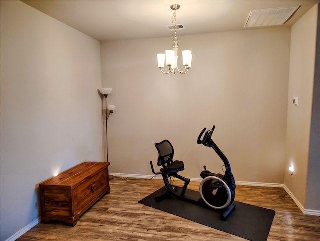 workout room with a chandelier and hardwood / wood-style flooring