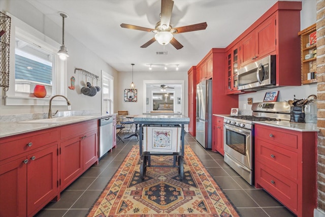 kitchen with pendant lighting, sink, stainless steel appliances, and dark tile patterned flooring