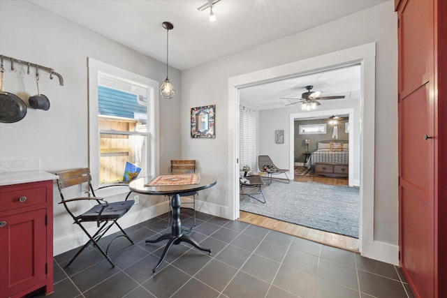 dining room with ceiling fan and dark tile patterned floors