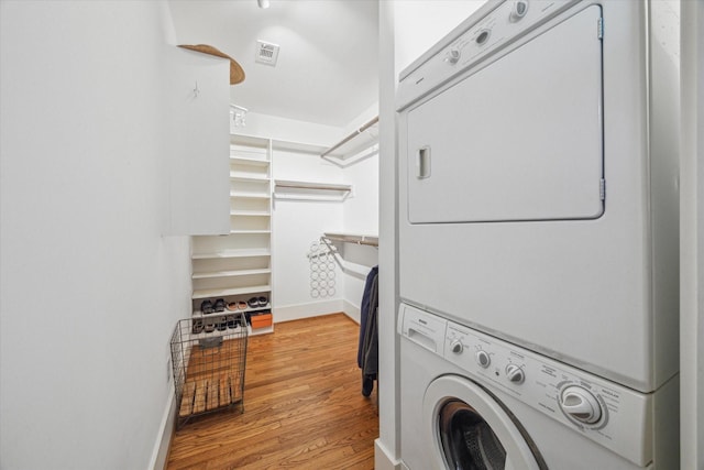 laundry area with light hardwood / wood-style floors and stacked washing maching and dryer