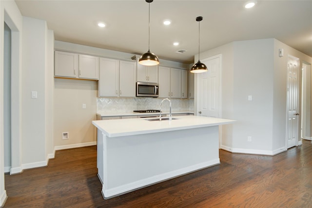 kitchen featuring decorative backsplash, dark hardwood / wood-style flooring, a kitchen island with sink, sink, and decorative light fixtures