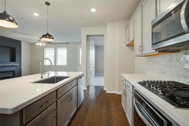 kitchen with tasteful backsplash, stainless steel appliances, ceiling fan, sink, and pendant lighting