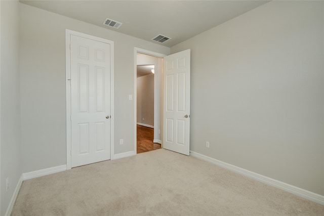 unfurnished bedroom featuring light carpet and a closet