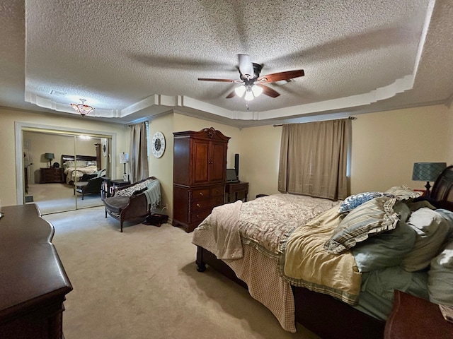 carpeted bedroom featuring ceiling fan, a raised ceiling, a textured ceiling, and a closet